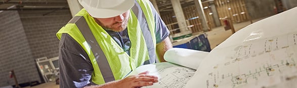 Worker looking through construction blueprints
