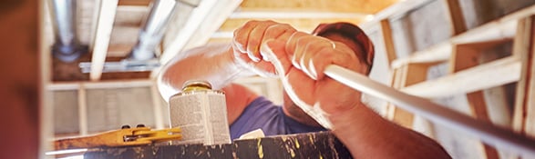 man installing cpvc pipe in tight space 