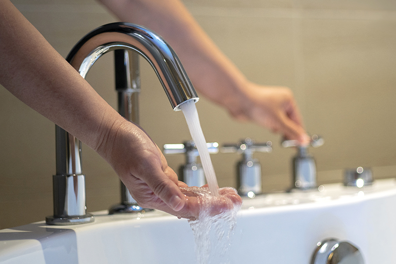 Person running bath water with hand under water